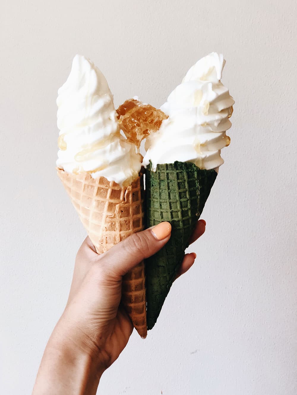 Two Honeymee soft-serve cones held together, one with a honeycomb chip